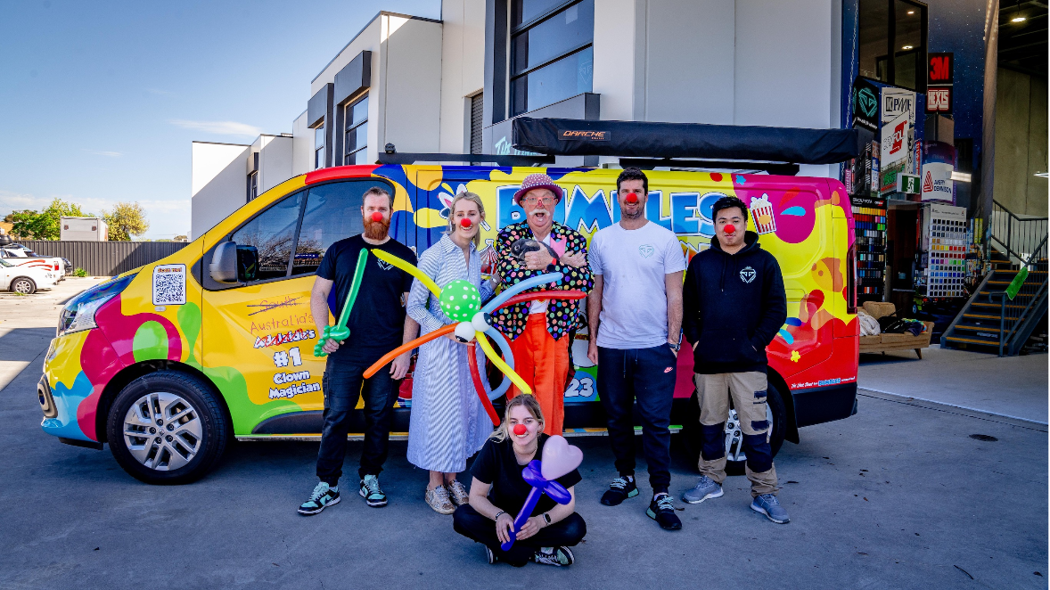 Andrew and five others posing outside a warehouse.